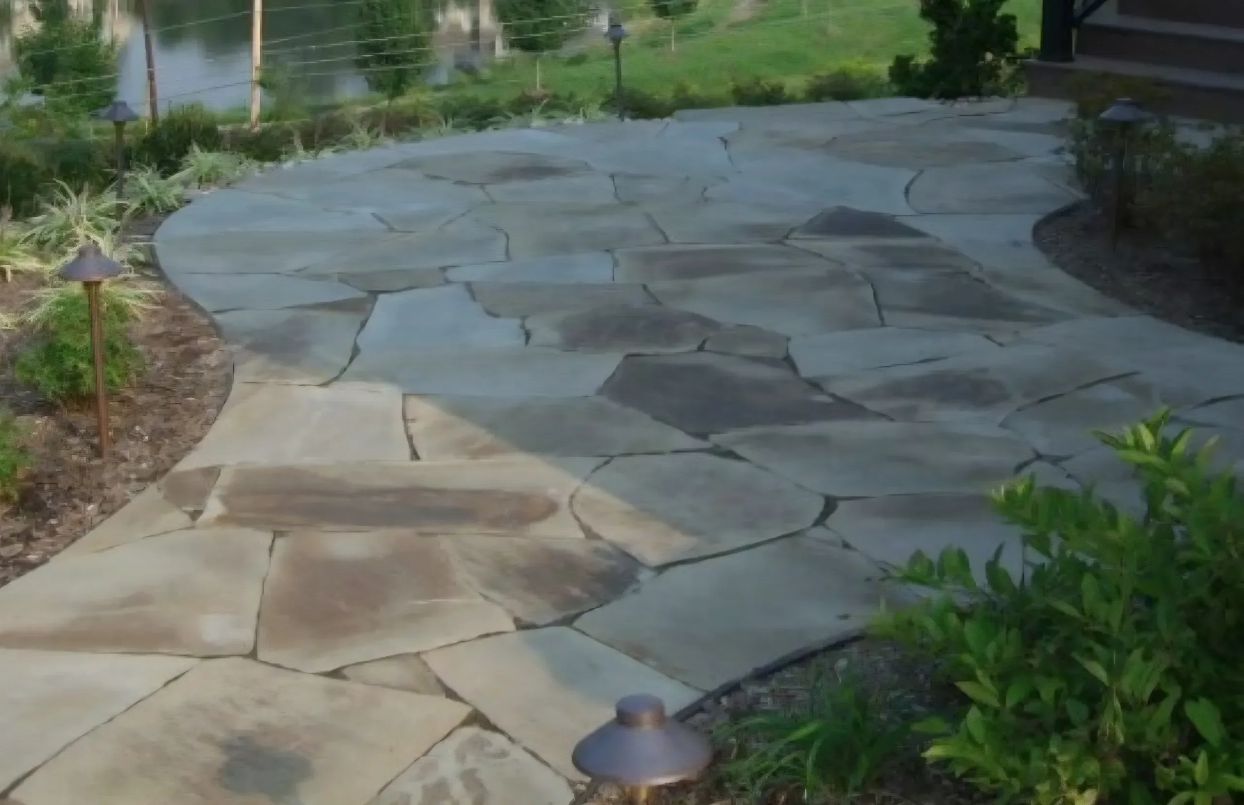 A winding flagstone path leads toward a waterfront view after sealing.