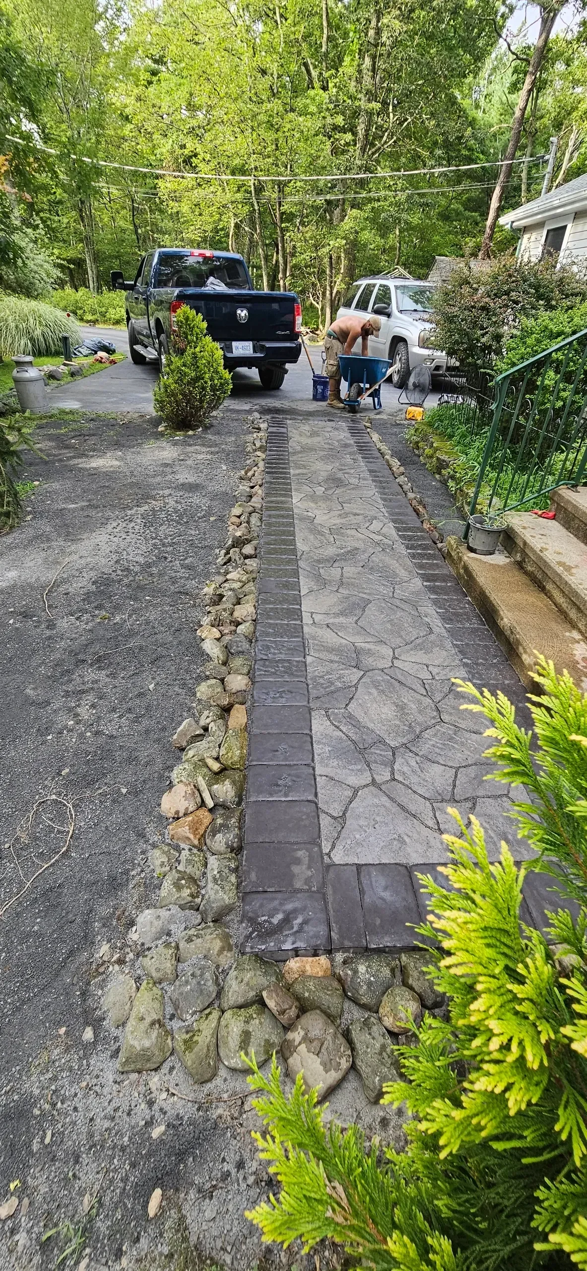 Crew members finish a curved paver walkway with natural stone edging.